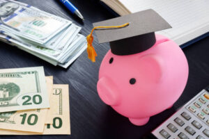 Savings for college and education. Pink piggy bank with graduation cap and money.