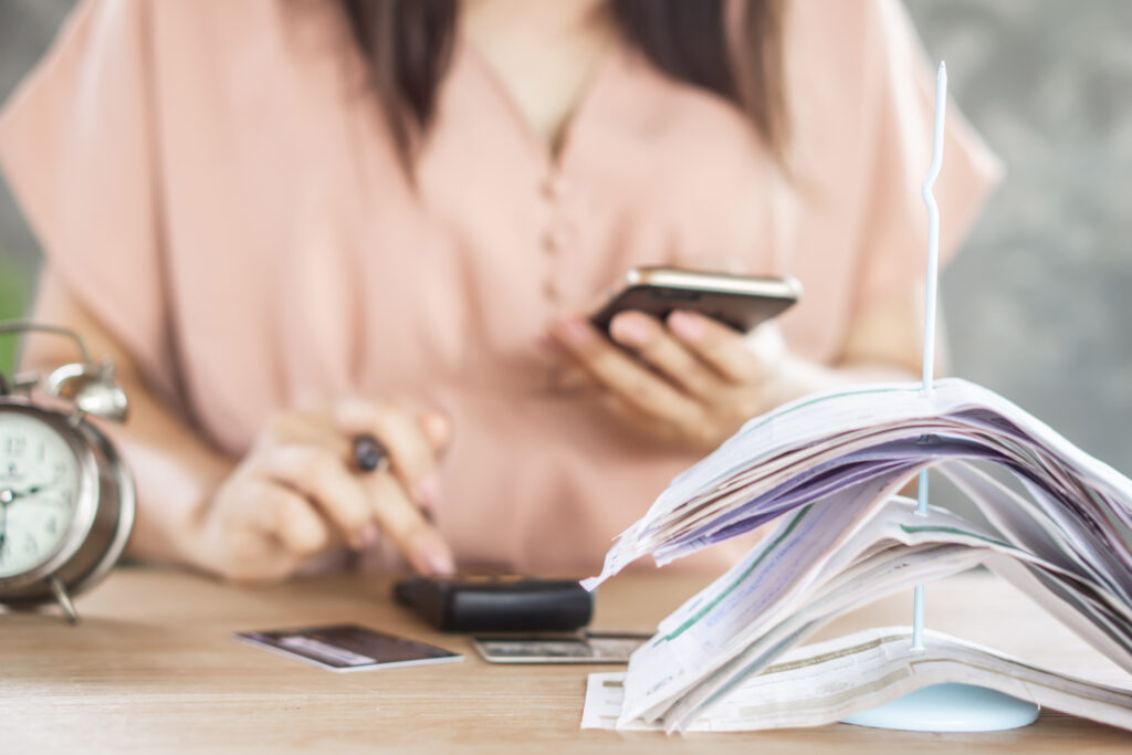 woman holding phone and using calculator