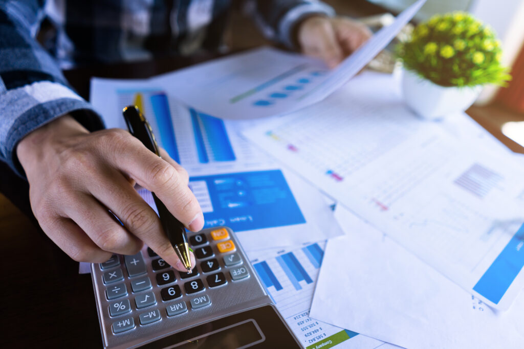 man holding papers and using calculator while holding pen